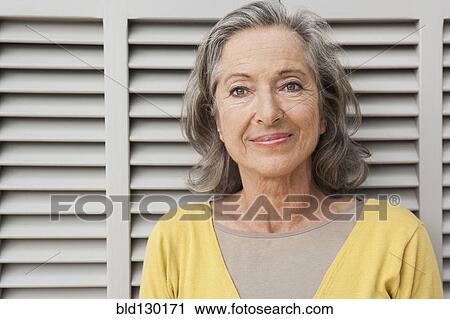Stock Image - Woman smiling by shutters. Fotosearch