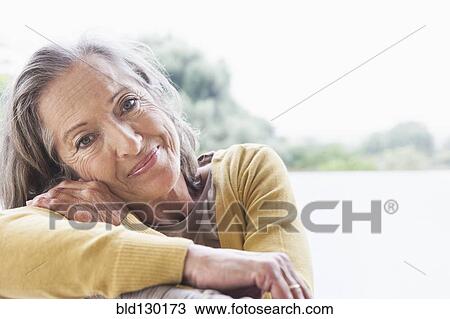 Stock Image - Woman smiling on sofa. Fotosearch
