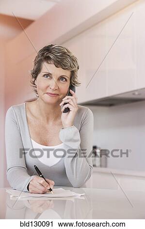 Woman taking notes and talking on phone View Large Photo Image Stock Image - Woman taking notes and talking on phone. Fotosearch