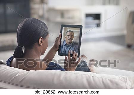 Stock Image - Woman video conferencing with father on digital tablet. Fotosearch