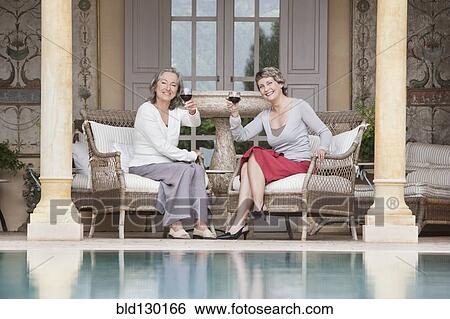 Women toasting each other by swimming pool View Large Photo Image Stock Photograph - Women toasting each other by swimming pool. Fotosearch
