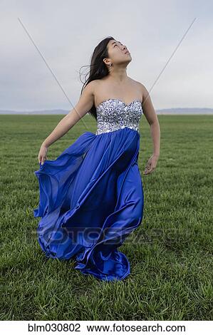 Stock Image - Asian teenage girl wearing gown in rural field. Fotosearch