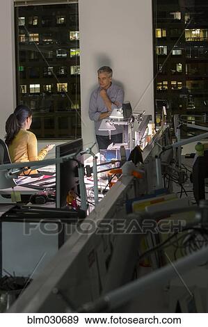 Stock Photo - Business people working late in office. Fotosearch
