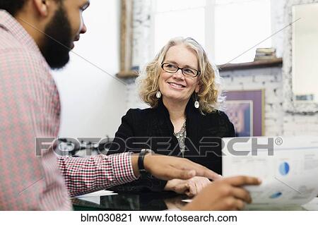 Stock Image - Businesswoman talking to young businessman. Fotosearch