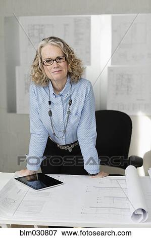Stock Photo - Caucasian architect standing at desk. Fotosearch