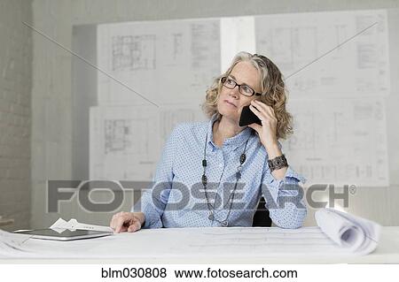 Caucasian architect talking on phone at desk View Large Photo Image Stock Photo - Caucasian architect talking on phone at desk. Fotosearch