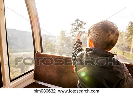 Stock Image - Caucasian boy looking out tram window. Fotosearch