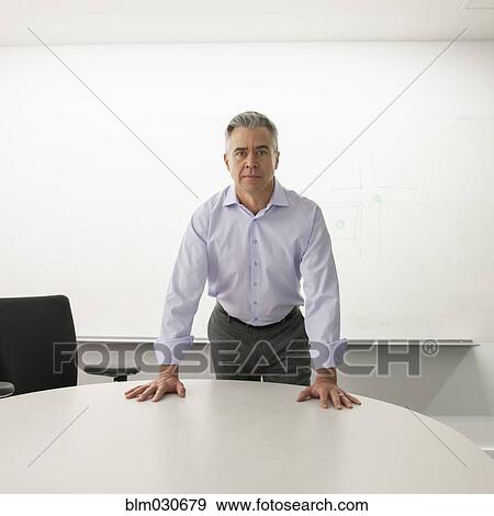 Stock Photo - Caucasian businessman standing at conference table. Fotosearch