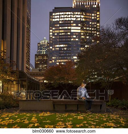 Stock Image - Caucasian businessman using laptop in urban courtyard. Fotosearch