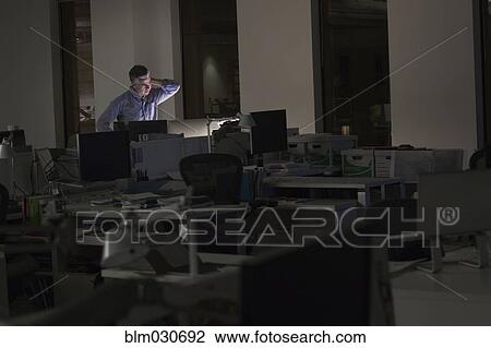 Stock Image - Caucasian businessman working late in office. Fotosearch