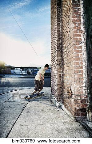 Stock Photo - Caucasian man riding skateboard on city street. Fotosearch