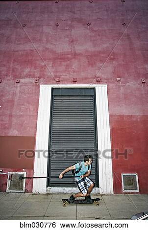 Stock Photograph - Caucasian man riding skateboard with land paddle. Fotosearch