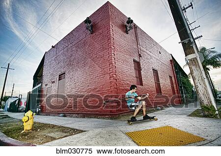 Stock Photography - Caucasian man riding skateboard with land paddle. Fotosearch