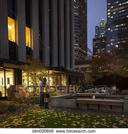 Stock Photo - Couple admiring skyscrapers in urban courtyard. Fotosearch