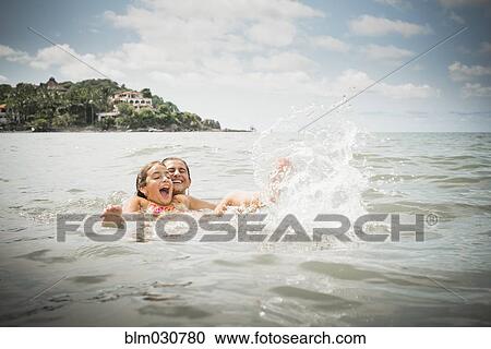 Stock Image - Father and daughter playing in lake. Fotosearch