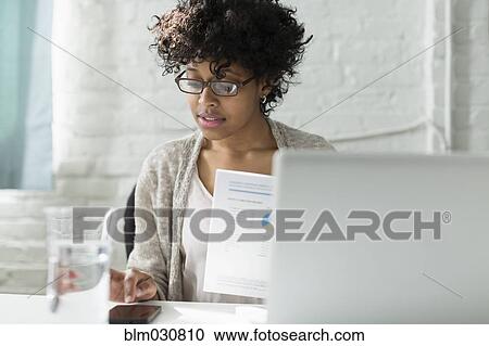 Stock Image - Mixed race architect working at desk. Fotosearch