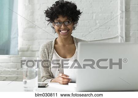 Stock Image - Mixed race architect working at desk. Fotosearch