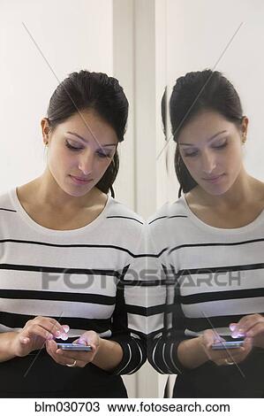 Stock Image - Mixed race businesswoman using cell phone. Fotosearch