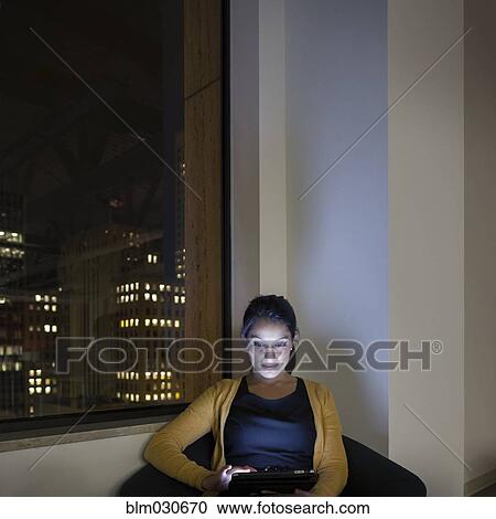 Stock Image - Mixed race businesswoman working late in office. Fotosearch