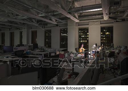 Stock Photo - Mixed race businesswoman working late in office. Fotosearch
