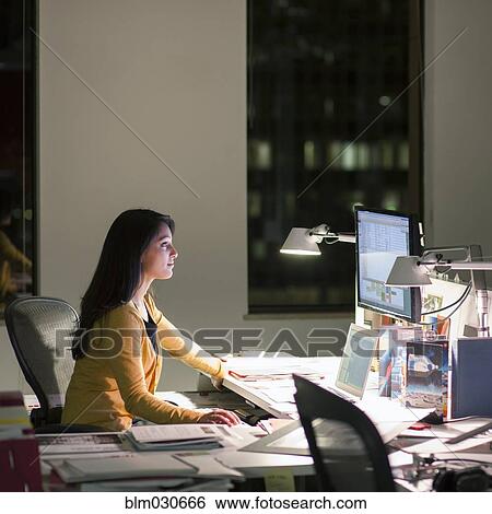 Stock Photograph - Mixed race businesswoman working late in office. Fotosearch