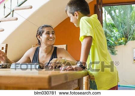 Stock Image - Mother and son talking at table. Fotosearch