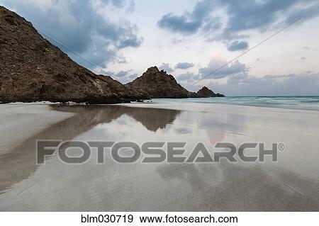Rocky coastline reflected in still beach surf View Large Photo Image Stock Photo - Rocky coastline reflected in still beach surf. Fotosearch