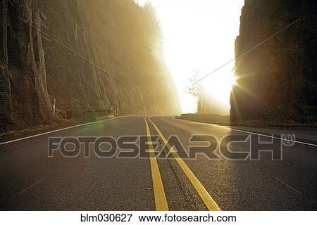 Stock Photo - Rural road cutting through mountains. Fotosearch