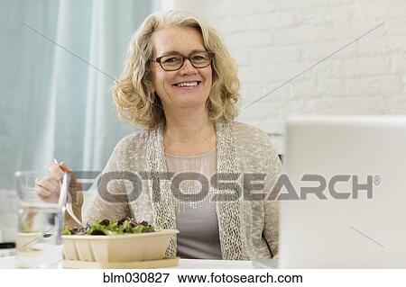 Stock Photo - Senior Caucasian businesswoman eating salad. Fotosearch