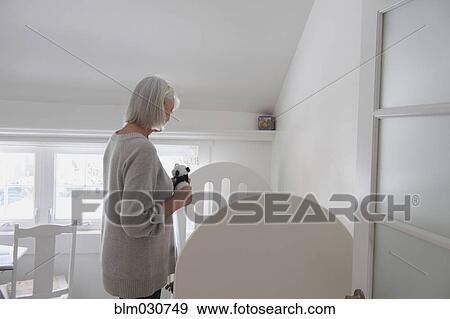 Stock Photo - Senior Caucasian woman admiring baby in crib. Fotosearch