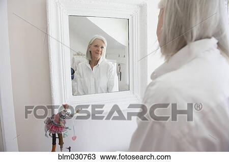 Stock Image - Senior Caucasian woman admiring herself in mirror. Fotosearch