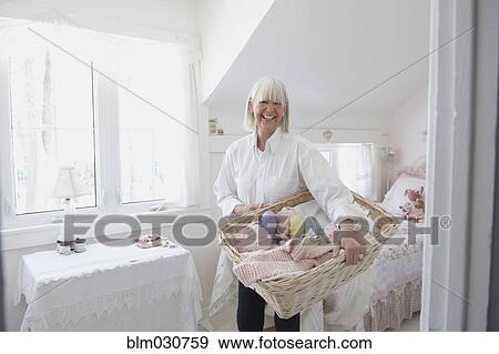 Stock Photo - Senior Caucasian woman holding basket of knitting. Fotosearch