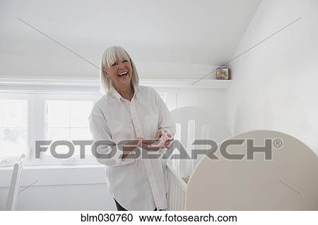 Stock Image - Senior Caucasian woman holding knitted baby bootie. Fotosearch