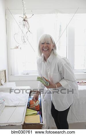 Senior Caucasian woman putting away baby clothes View Large Photo Image Stock Image - Senior Caucasian woman putting away baby clothes. Fotosearch