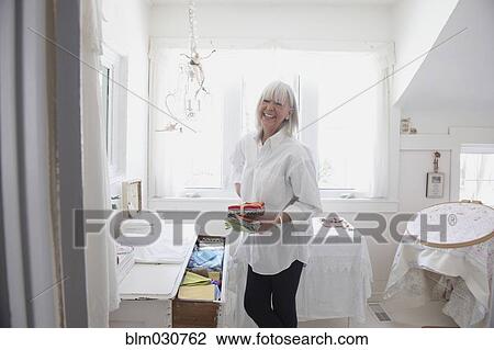 Stock Image - Senior Caucasian woman putting away baby clothes. Fotosearch
