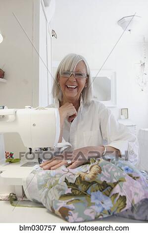 Stock Photo - Senior Caucasian woman sewing blanket. Fotosearch