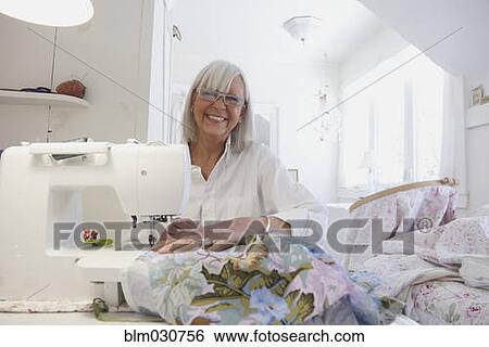 Stock Photograph - Senior Caucasian woman sewing blanket. Fotosearch