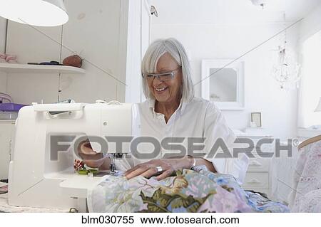 Stock Photography - Senior Caucasian woman sewing blanket. Fotosearch