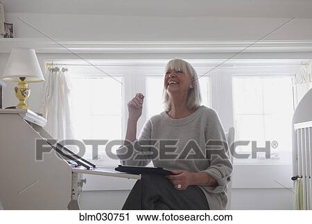 Senior Caucasian woman sitting at desk View Large Photo Image Stock Image - Senior Caucasian woman sitting at desk. Fotosearch