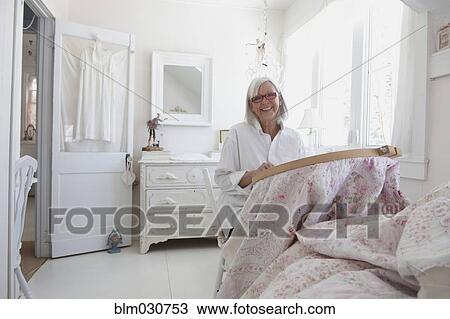 Stock Image - Senior Caucasian woman stitching blanket. Fotosearch
