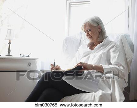 Stock Photography - Senior Caucasian woman writing in journal. Fotosearch