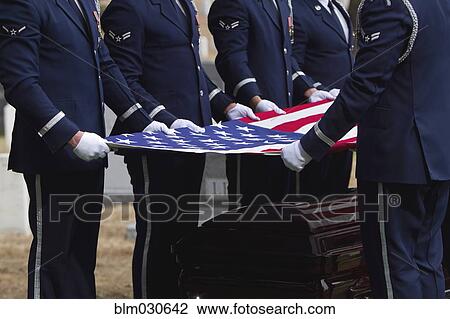 Stock Image - Soldiers folding flag at military funeral. Fotosearch