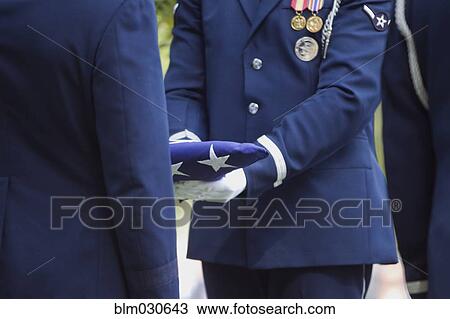 Stock Image - Soldiers folding flag at military funeral. Fotosearch
