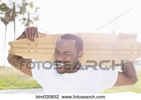 African American man carrying skateboard outdoors View Large Photo Image Stock Image - African American man carrying skateboard outdoors. Fotosearch