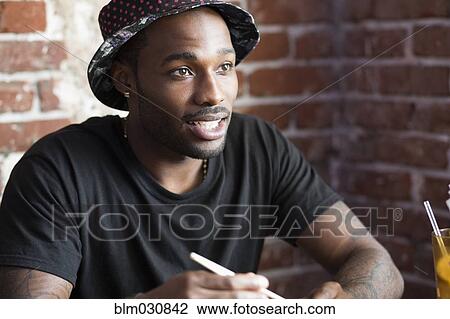 Stock Image - African American man sitting in cafe. Fotosearch