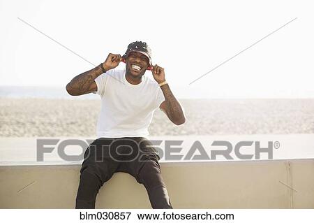 Stock Photo - African American man smiling on beach wall. Fotosearch