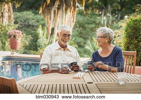 Stock Image - Caucasian couple playing cards outdoors. Fotosearch