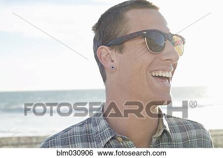 Stock Photograph - Caucasian man laughing on beach. Fotosearch