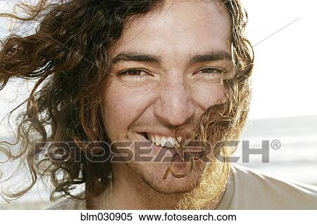 Stock Photography - Caucasian man smiling on beach. Fotosearch