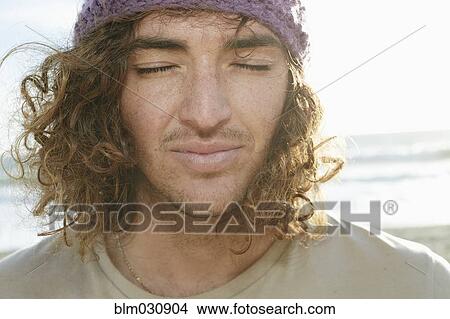 Picture - Caucasian man with eyes closed on beach. Fotosearch
